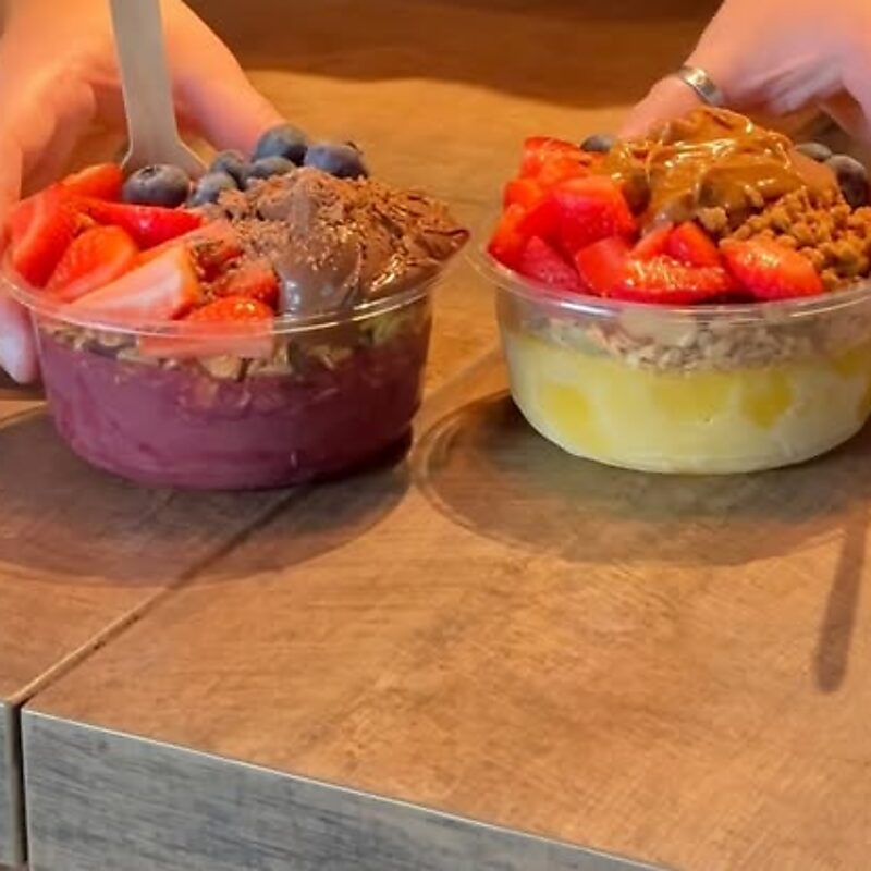 Two açai bowls topped with strawberries, blueberries and granola